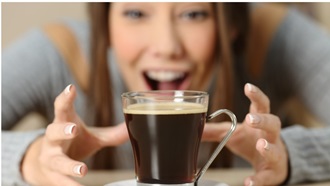une jeune femme souriante approche ses mains d'une tasse de café